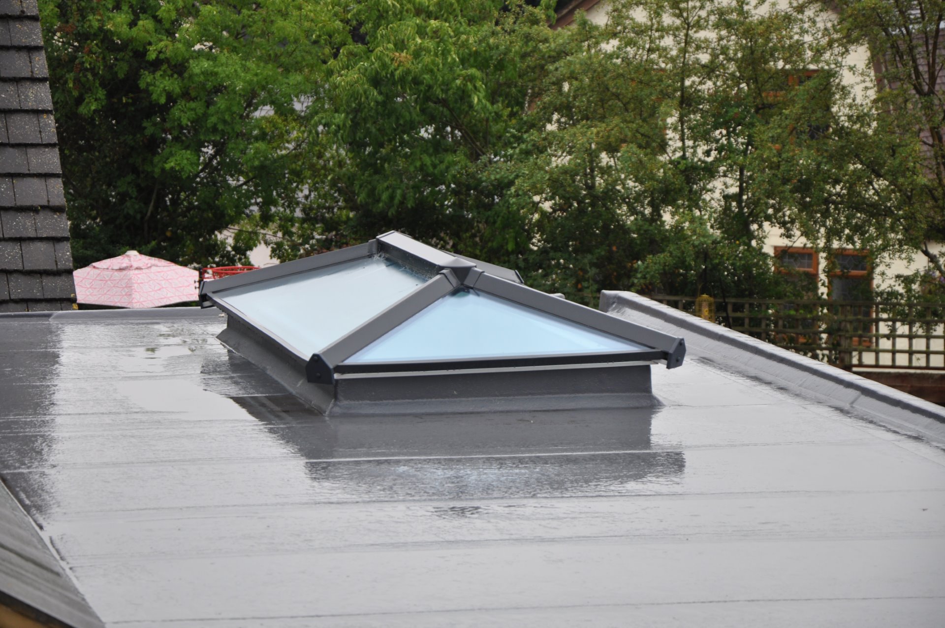 Contemporary, modern, luxury, double glazed glass roof lantern or light on a grey flat roof building or extension. Rainy autumn day, with reflections in rainwater on the roof surface Flat Roofing in Local
